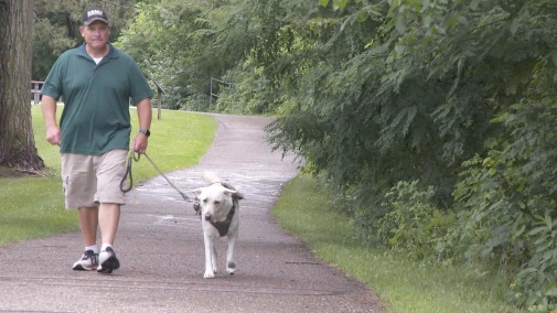 An image of a man with PTSD walking walking his dog.